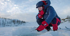 Girl wearing insulating primaloft jacket ice fishing with mormyshka ----Jente med isolerende jakke i primaloft fisker p� isen med mormyshka