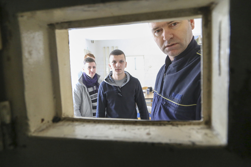 Unge romenere ser ut gjennom fengselsluke