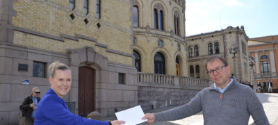 Lene Vågslid tar imot forslaget fra Audun Bringsvor foran Stortinget. Foto: Sigbjørn Larsen