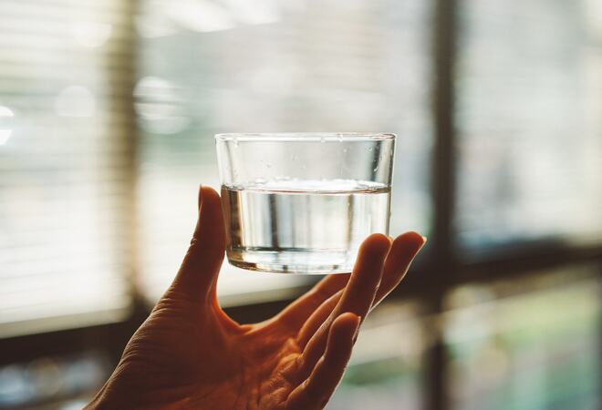 En hånd holder opp et glass med vann