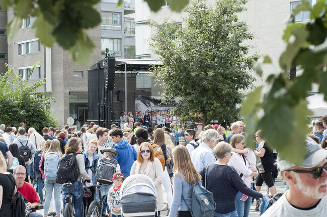 Foto fra sommertoget i Ås sentrum med mange mennesker i gågaten