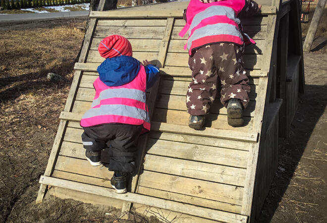 Fotografi av to små barn som klatrer opp et klatrestativ