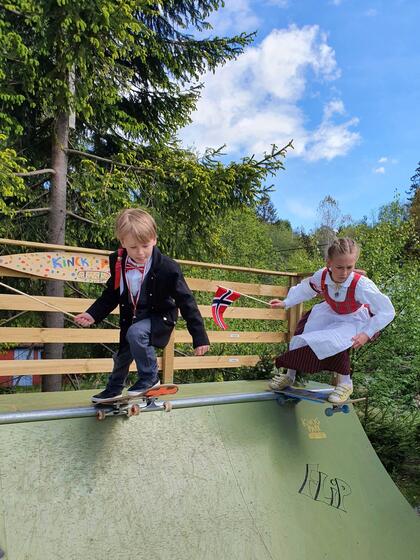 To barn på skateboard i 17. mai klær