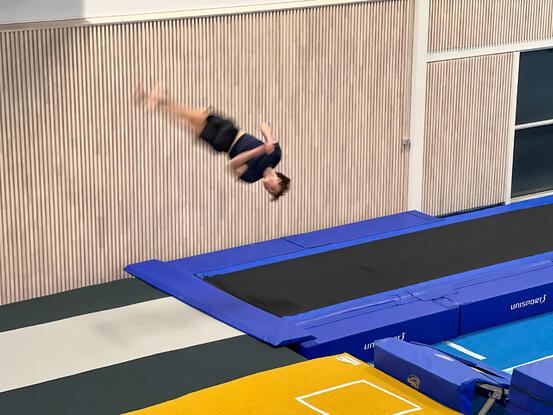 En ung mann tar et høyt hopp på trampolinen