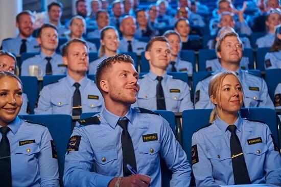 Fengselsbetjentaspiranter i uniform sitter i forelesningssal