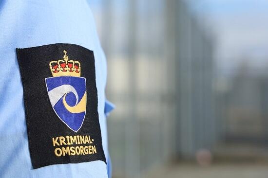 Bilde av en fengselsbetjents skjorteskulder med kriminalomsorgens emblem