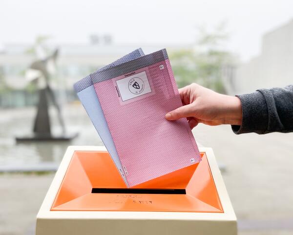 En rød stemmeseddel for kommunestyrevalg og en blå for fylkestingsvalg er på vei ned i en valgurne
