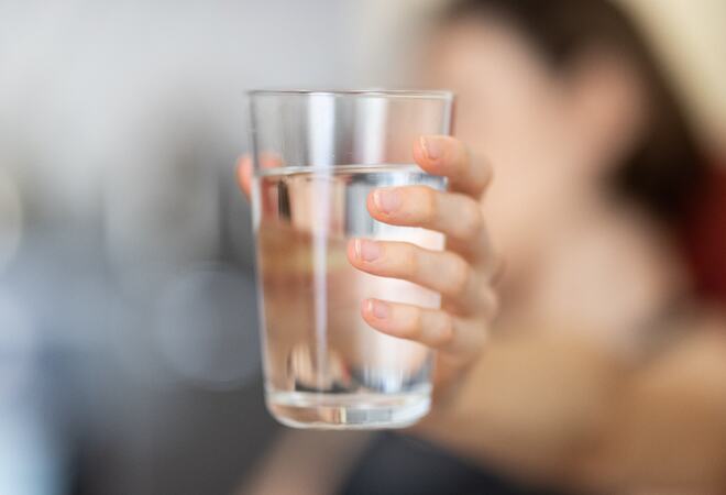 En hånd holder et glass med vann