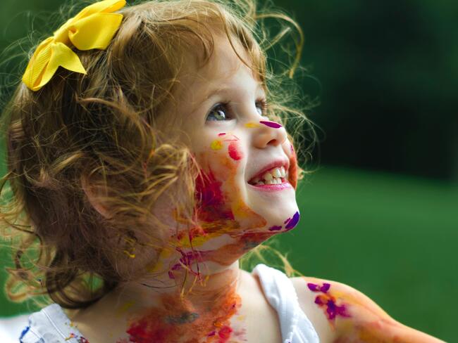 Portrett av liten jente med maling i ansiktet og gul sløyfe