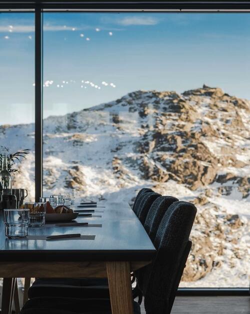 Bord og stoler med snødekket fjellandskap i bakgrunnen