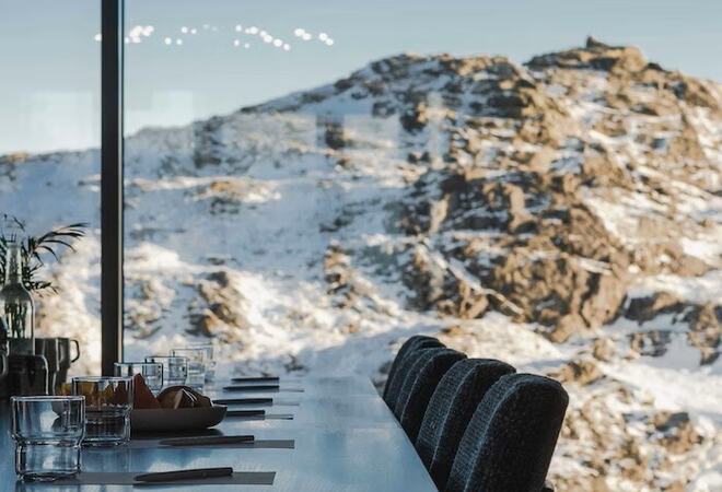 Bord og stoler med snødekket fjellandskap i bakgrunnen