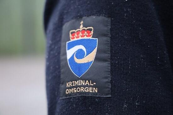 Fengselsbetjent iført kriminalomsorgens logo på genserermet