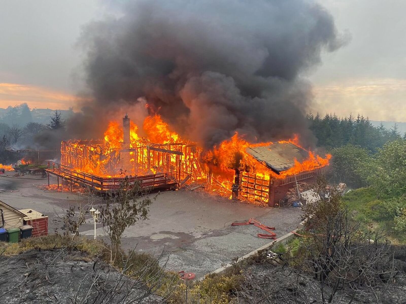 Brannvesenet måtte evakuere fra slukningsarbeidet i et hus i full fyr på Sotra utenfor Bergen. Foto: Bergen brannvesen