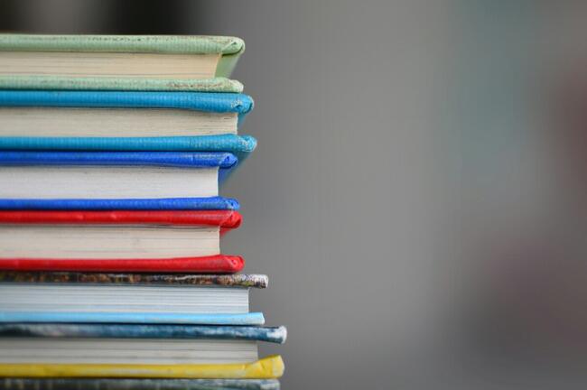 En bunke med fargerike skrivebøker på et bord