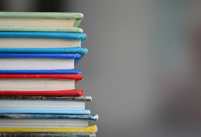 En bunke med fargerike skrivebøker på et bord