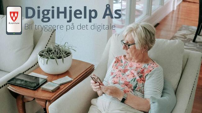 En dame sitter med mobilen i hånden og en laptop på bordet