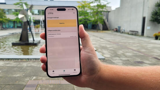 Foto av en hånd som holder opp en mobil med Civis-appen åpen