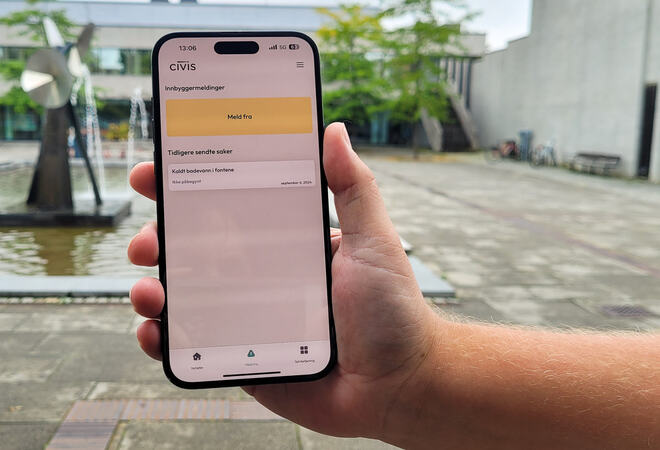 Foto av en hånd som holder opp en mobil med Civis-appen åpen