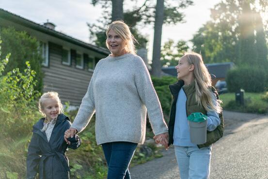 En voksen dame går med bøsse sammen med to barn