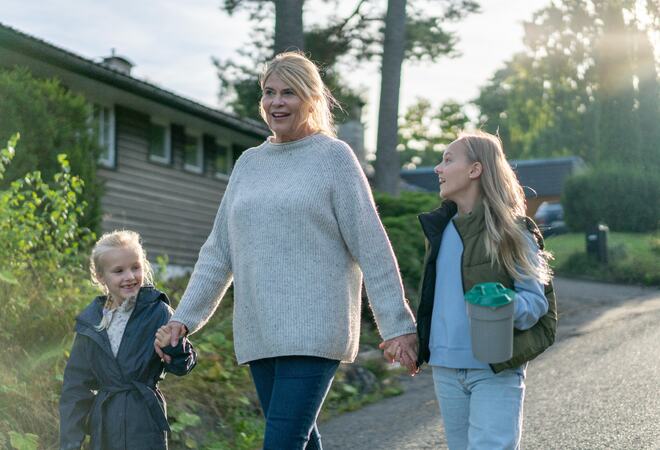 En voksen dame går med bøsse sammen med to barn