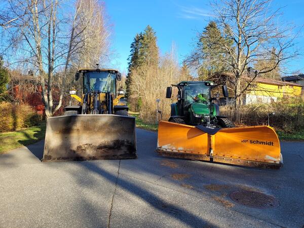 Hjullaster med skuff og traktor med brøyteskjær står ute i Hogstvedtveien