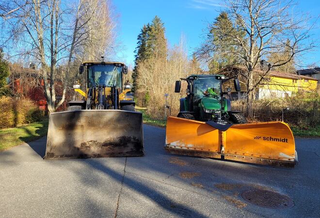 Hjullaster med skuff og traktor med brøyteskjær står ute i Hogstvedtveien