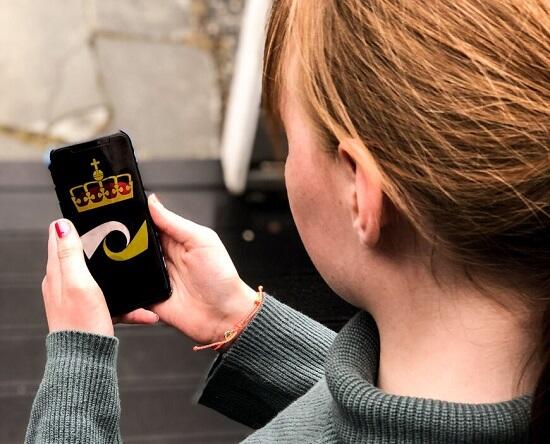 Person ser ned på en telefon som har kriminalomsorgens logo