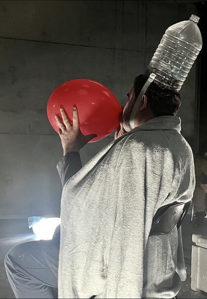 Foto av en mann i hvit kåpe, papirkrone som blåser en rød ballong