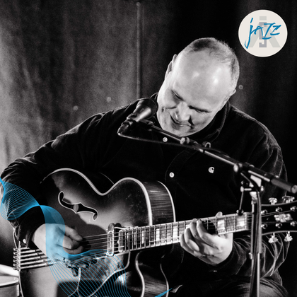 Sort og hvit foto av en mann som spiller gitar