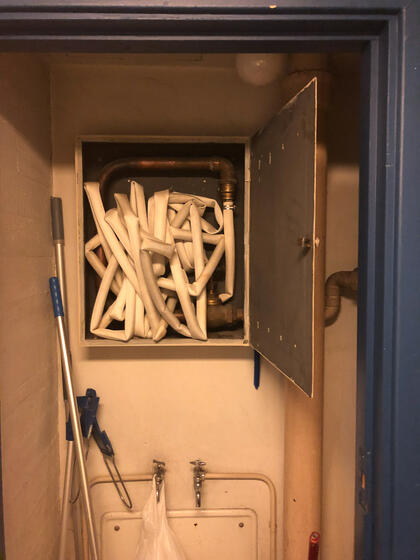 Bildet viser en brannslange som ligger sammenkrøllet inne i skapet, noe som hindrer uttrekk og gjør at den ikke vil fungere som forutsatt i en nødsituasjon. Forholdet tyder på manglende internkontroll og utilstrekkelig vedlikehold. Avvik fra god brannsikring