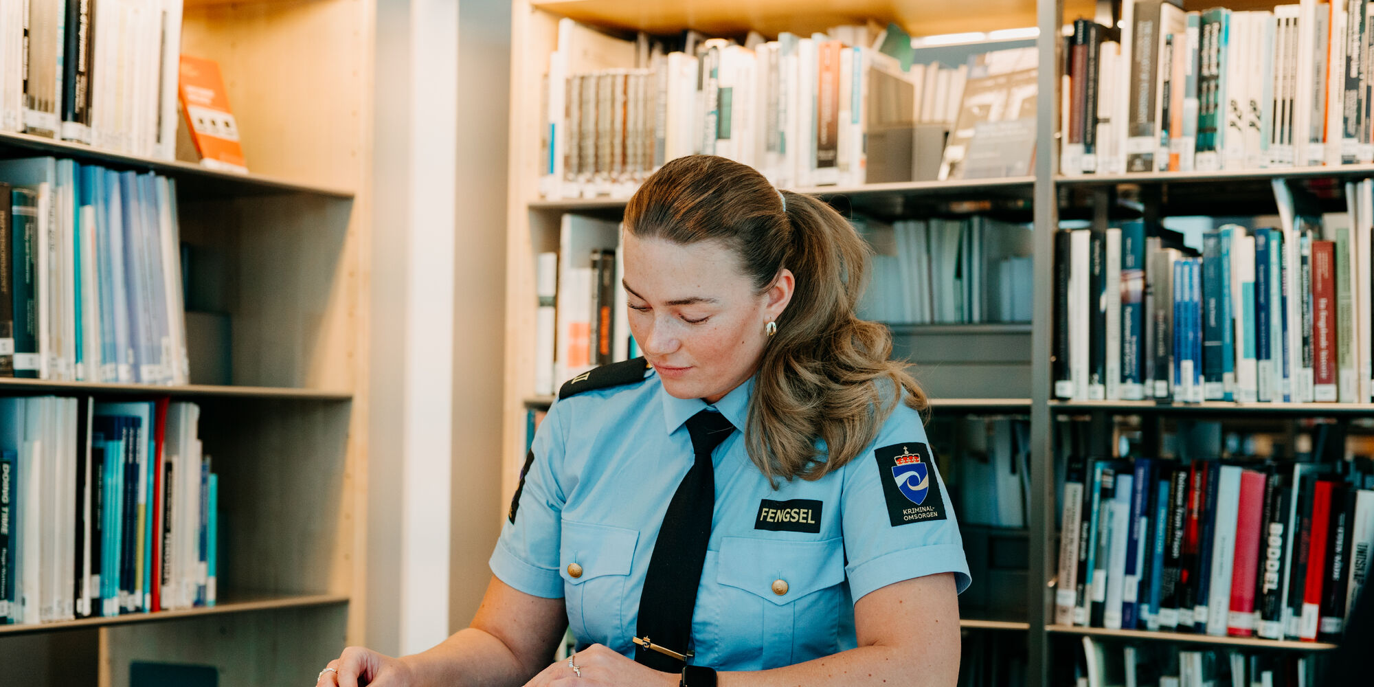 Aspirant sitter i biblioteket og leser