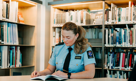 Aspirant sitter i biblioteket og leser