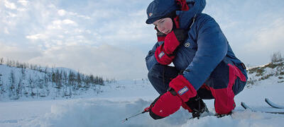 Girl wearing insulating primaloft jacket ice fishing with mormyshka ----Jente med isolerende jakke i primaloft fisker p� isen med mormyshka