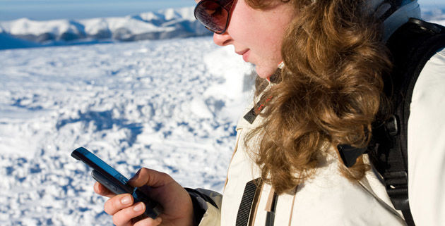 Female skier writing message from her cell phone